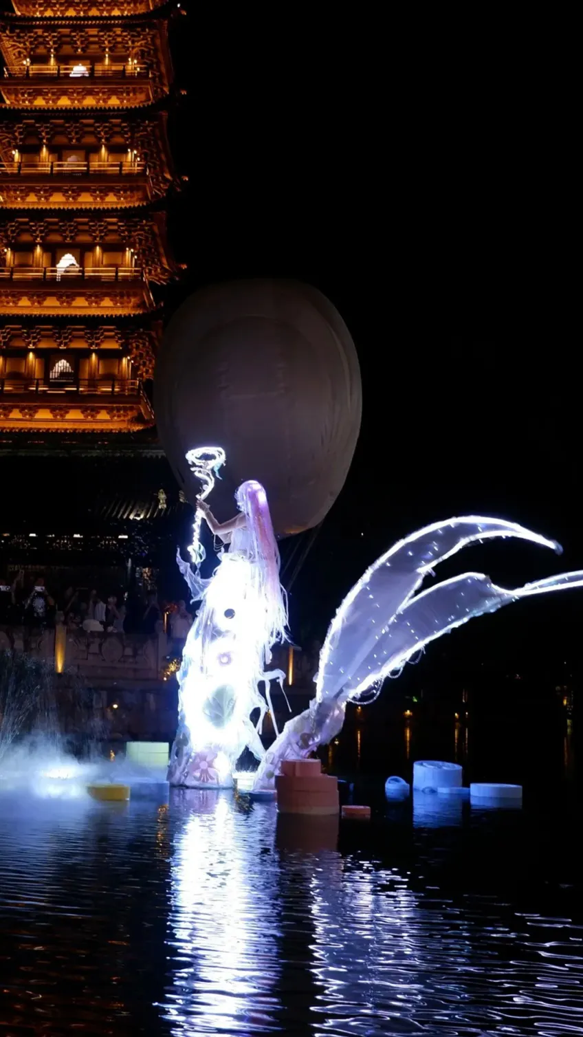 夜色中白莲塔与水面发光造型表演