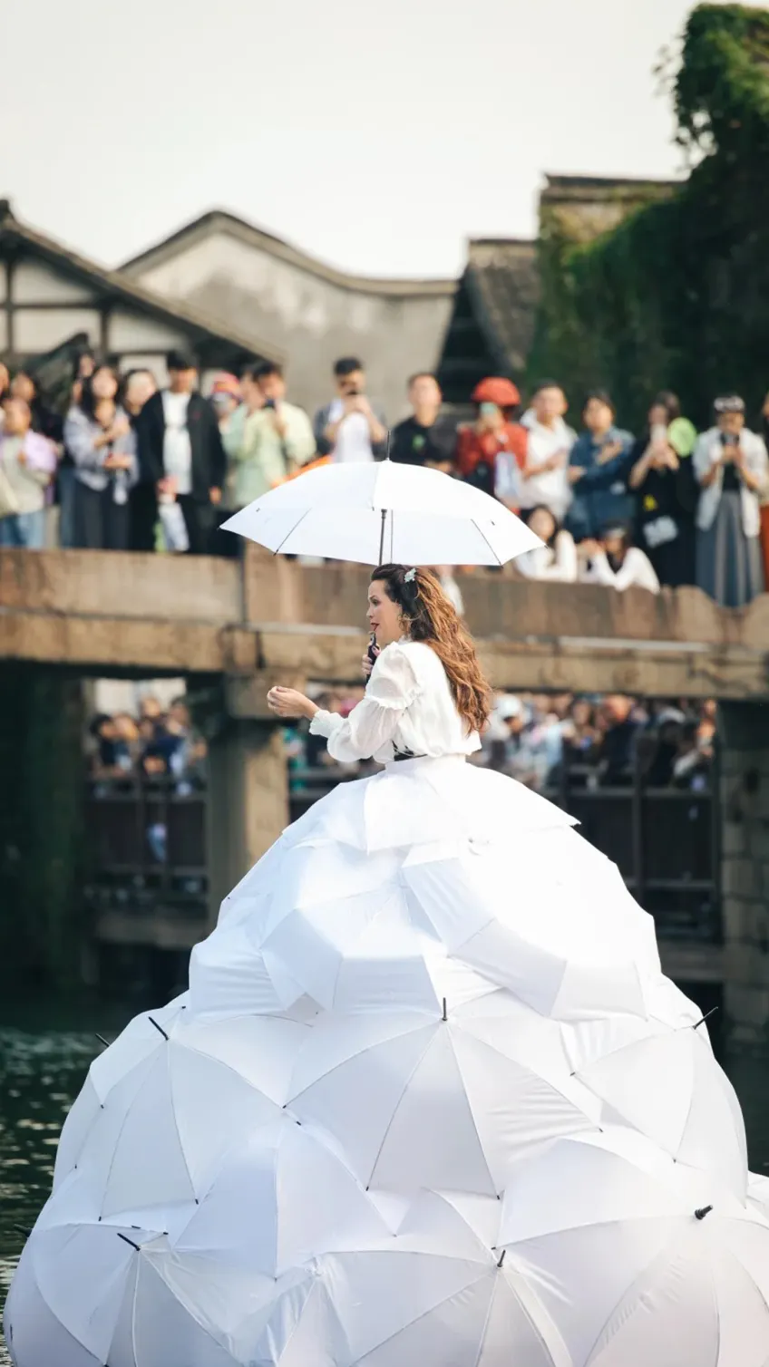 女演员着白伞裙在运河桥畔表演