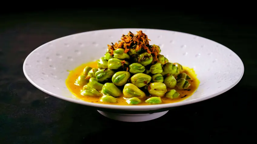 白盘金字塔形翠绿蚕豆顶缀深色干菜特写