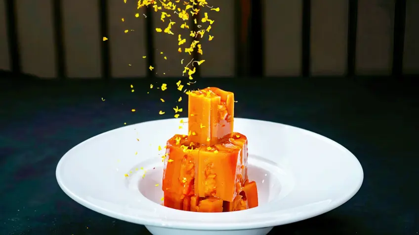 白盘琥珀色糖藕块洒落桂花瓣特写