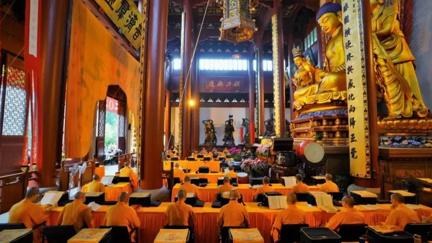 灵隐寺殿内橙衣僧众对金身佛像诵经