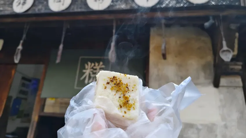 手持冒热气的粉团与糕字招牌