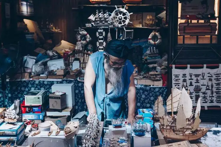 白鬚匠人在作坊桌前製作木船模