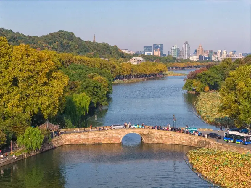 西泠一带车行石拱桥公交行人与远处城景