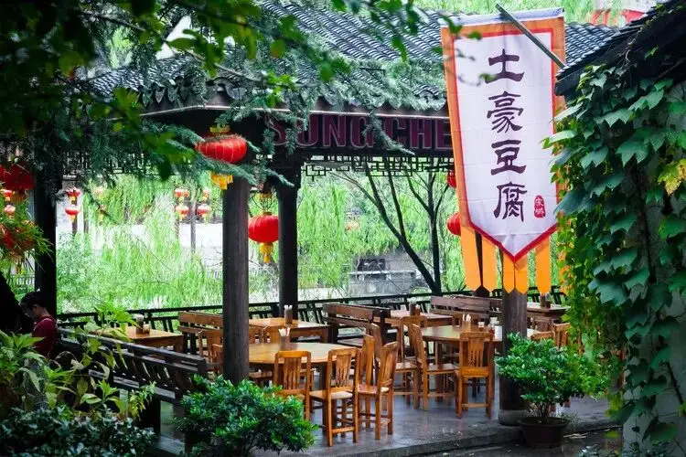 土豪豆腐豎幅招牌與廊外桌椅柳樹