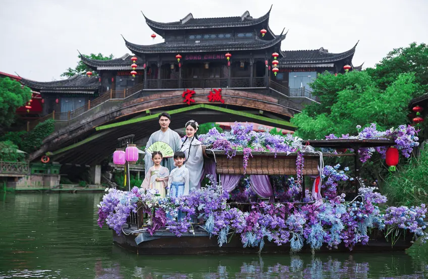 漢服家庭立於花飾遊船宋城廊橋背景