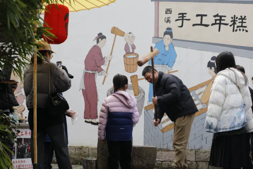 游客持木槌石臼打年糕壁画背景