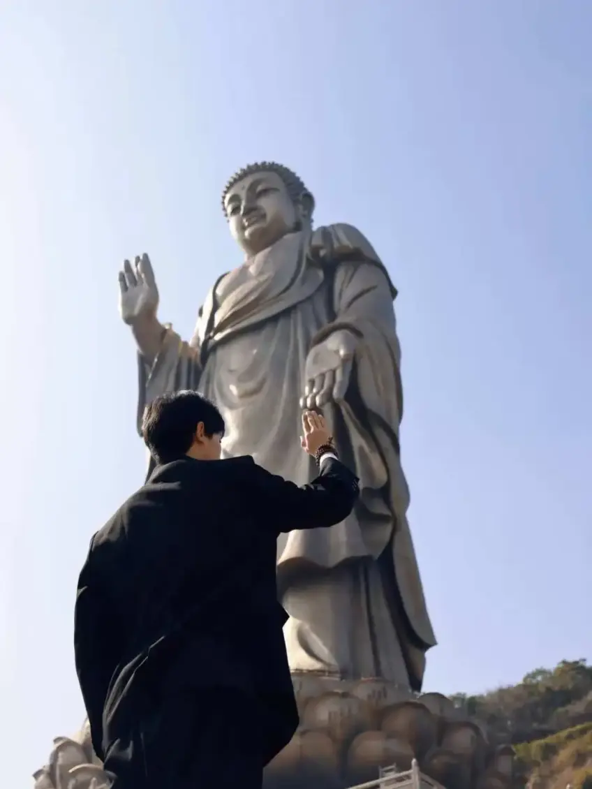 游客背影举手与灵山大佛左手击掌合影