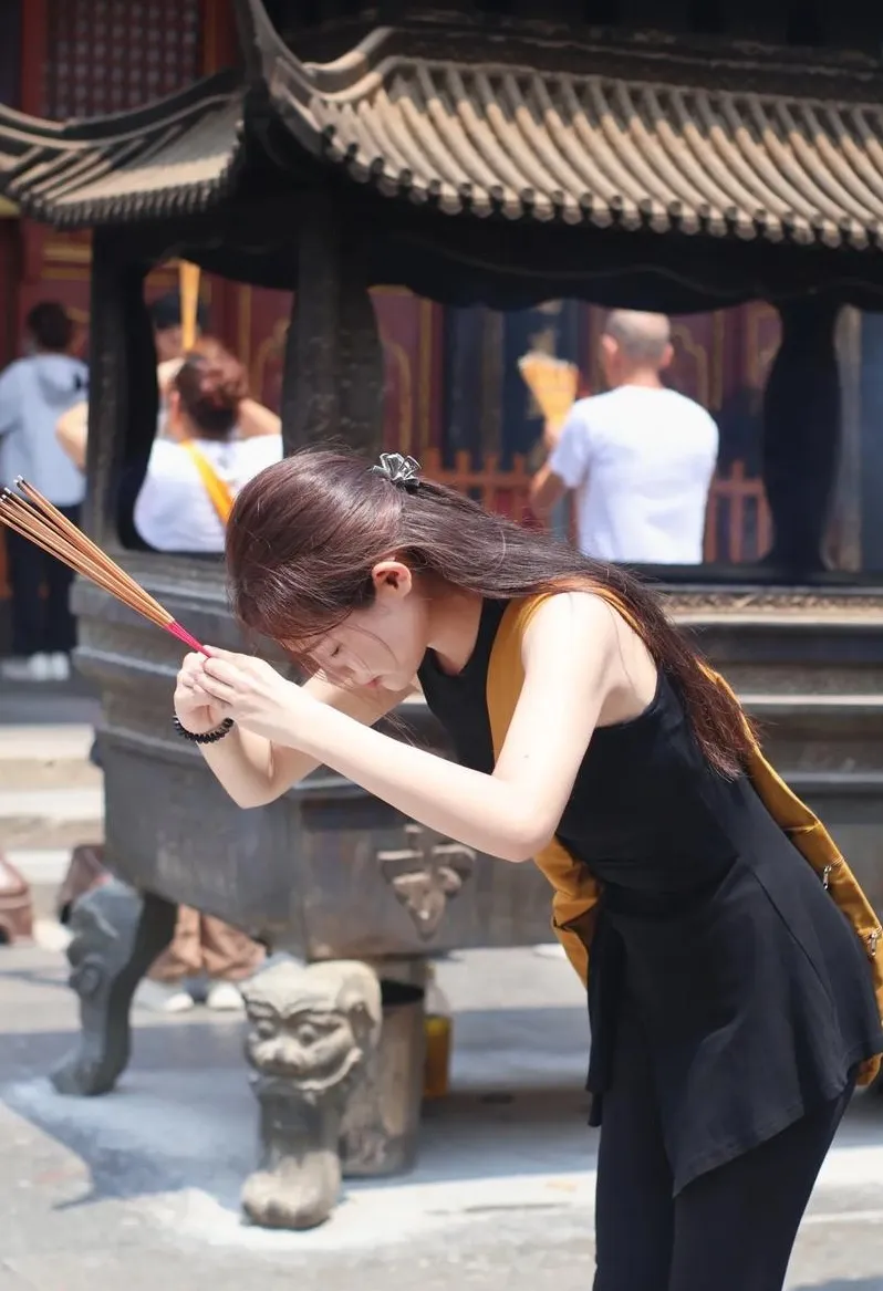 信众双手持香合十鞠躬祈福