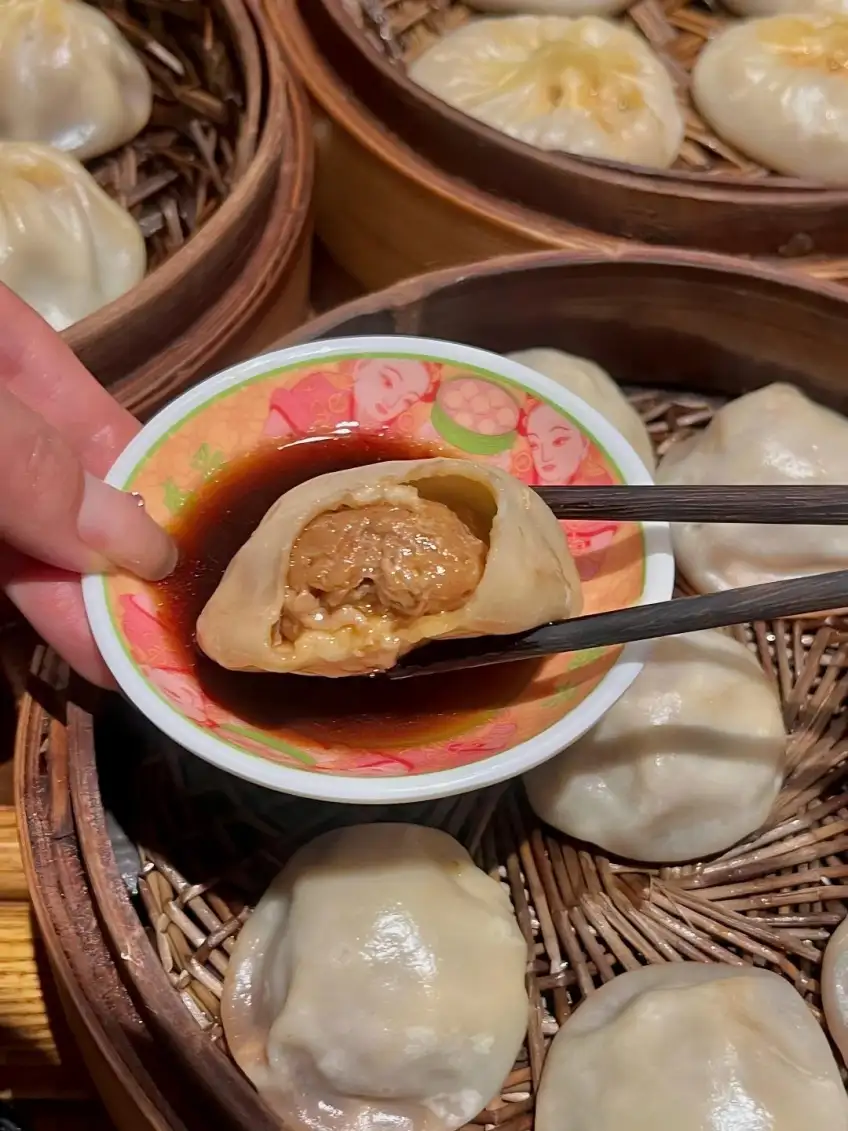 筷子夹开汤包蘸醋露出肉馅