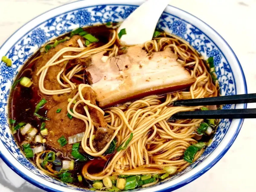 青花碗红汤焖肉面筷子挑起