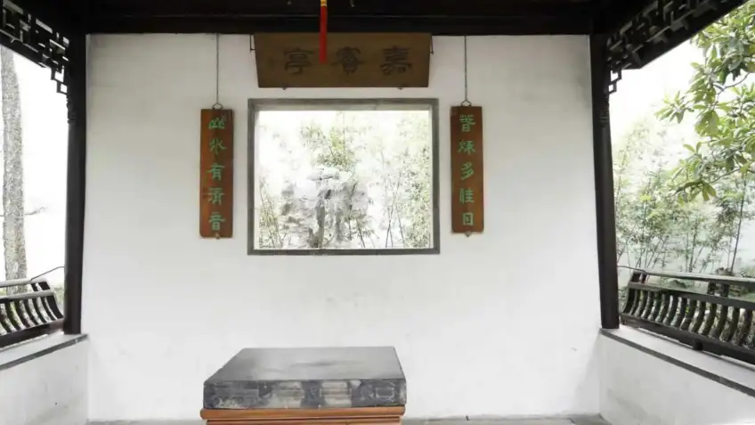 嘉宝亭横匾下窗框框住竹石庭院