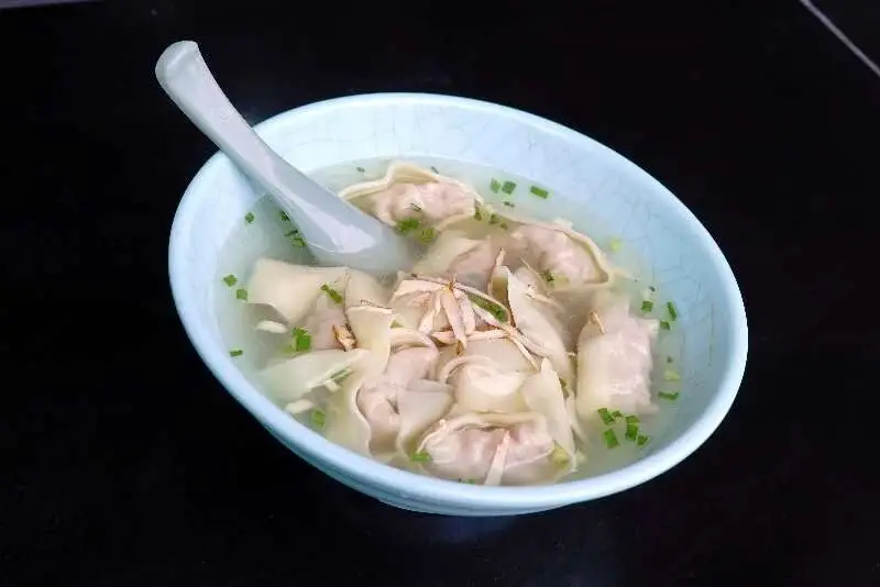 淺藍碗裡清湯餛飩與勺子