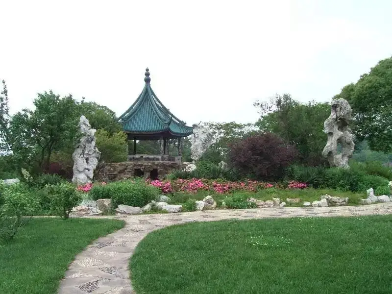梅园奇石圃青绿亭子与粉红花卉环绕石径