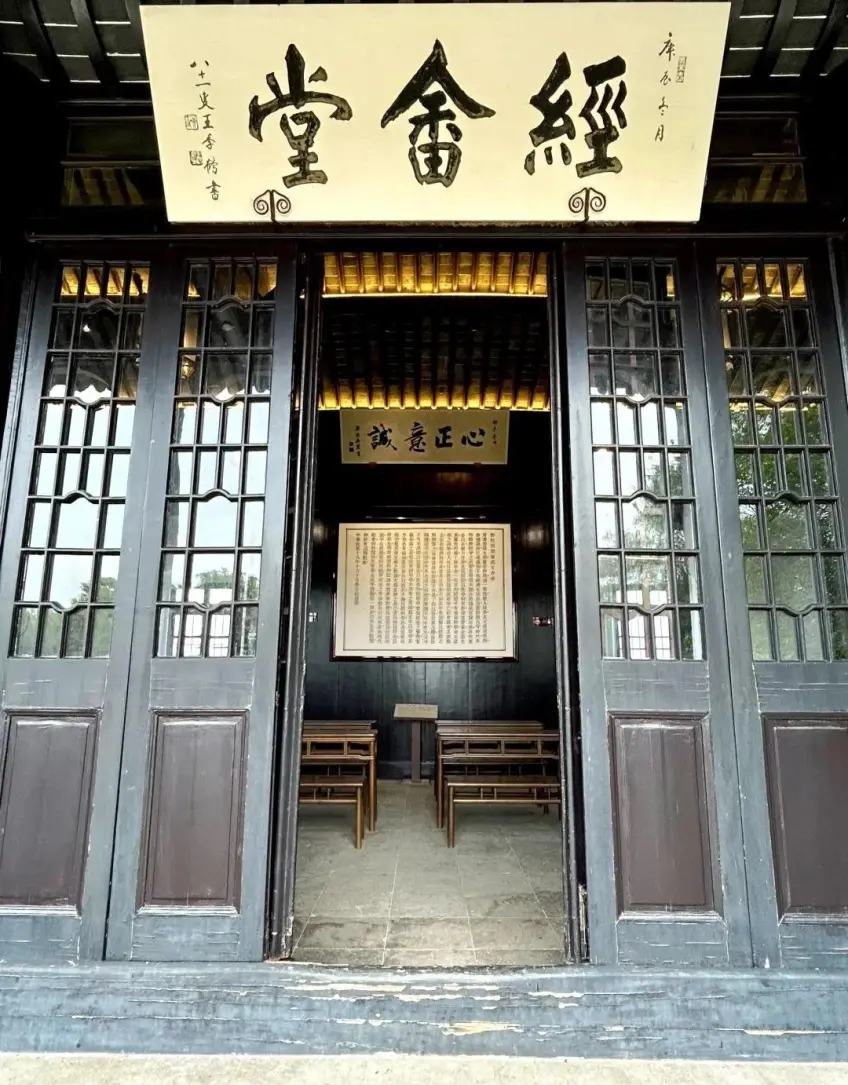 梅园经畲堂匾额敞开木门内可见课桌椅
