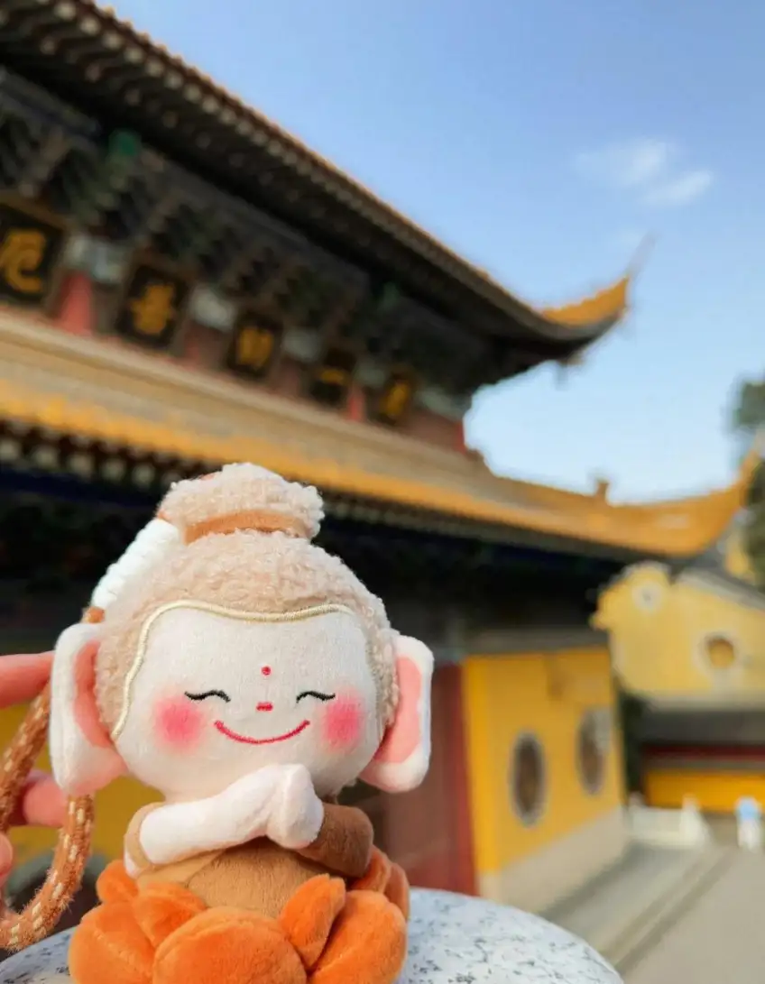 豎圖合十佛寶寶掛件黃牆藍天下