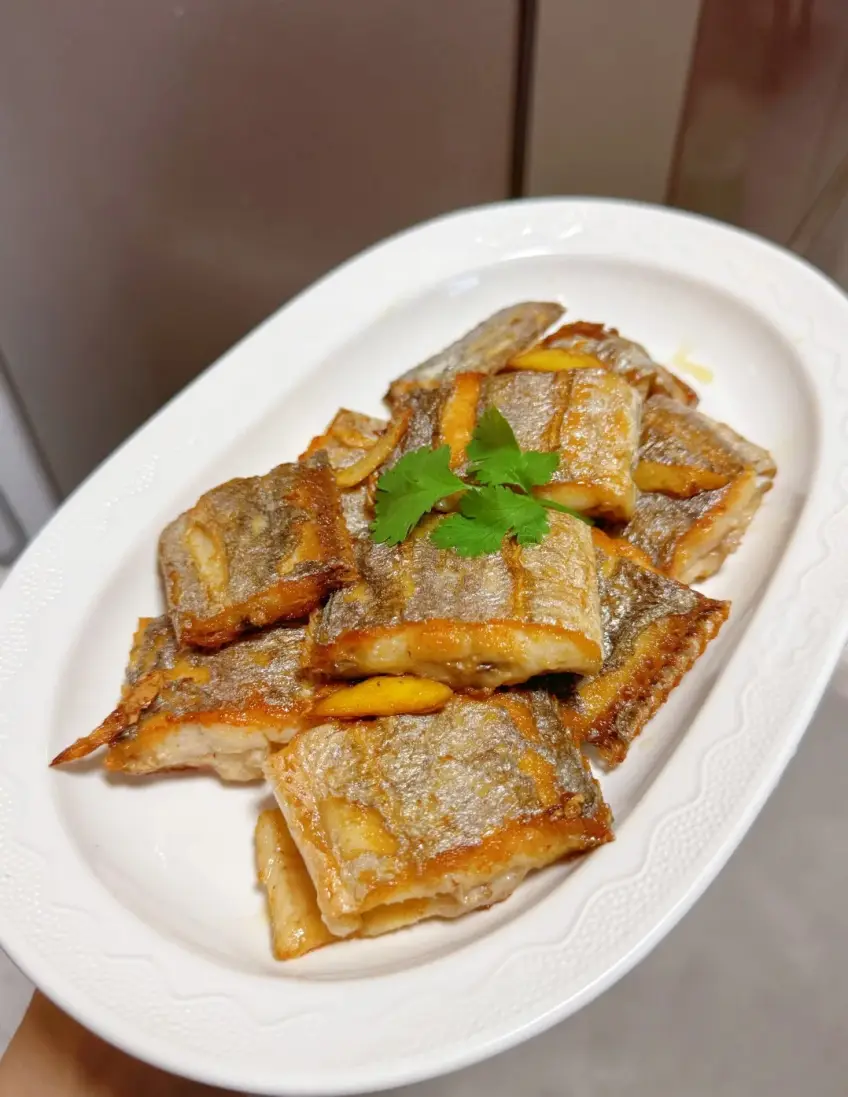 香煎帶魚段配香菜薑片的白盤裝盤示意