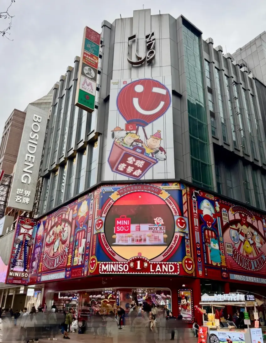 名創優品全球壹號店夜景角門頭與同樓招牌示意