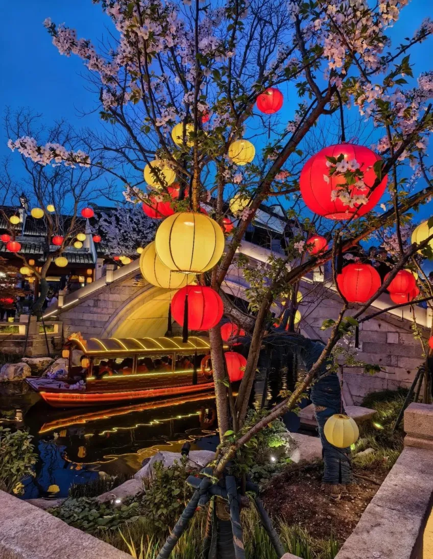 竖向示意：河塘夜色红灯笼樱花与游船石桥