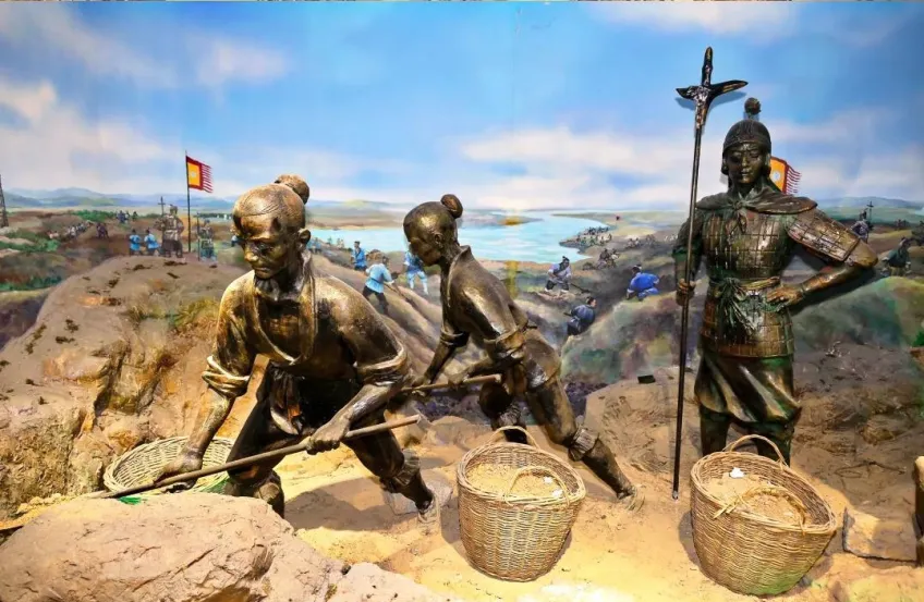 运河厅工程场景雕塑：劳工撬石与持械人物，背景为施工壁画