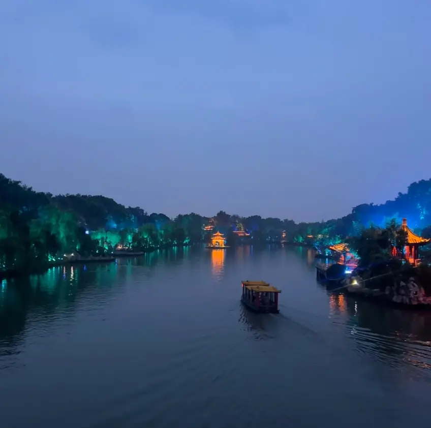 瘦西湖夜色中画舫沿湖岸灯光航道前行