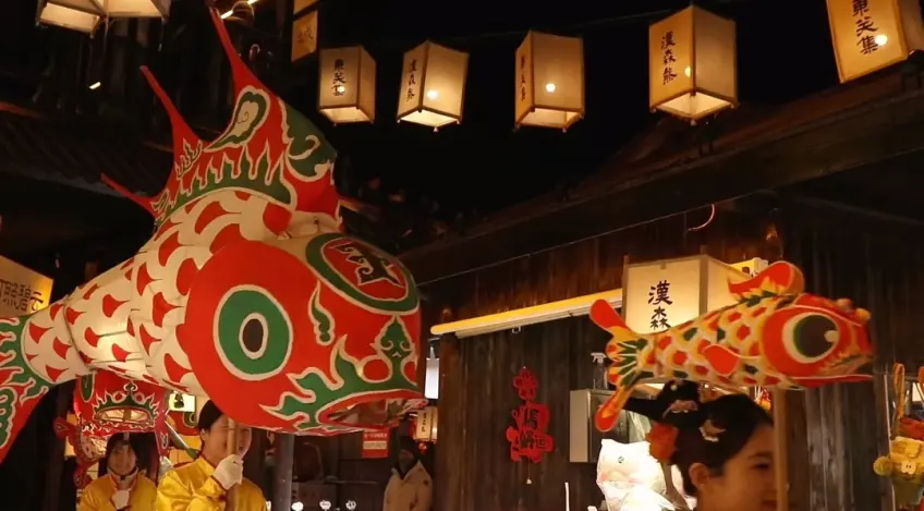 表演者手持大型彩色鱼灯在东关街夜巡
