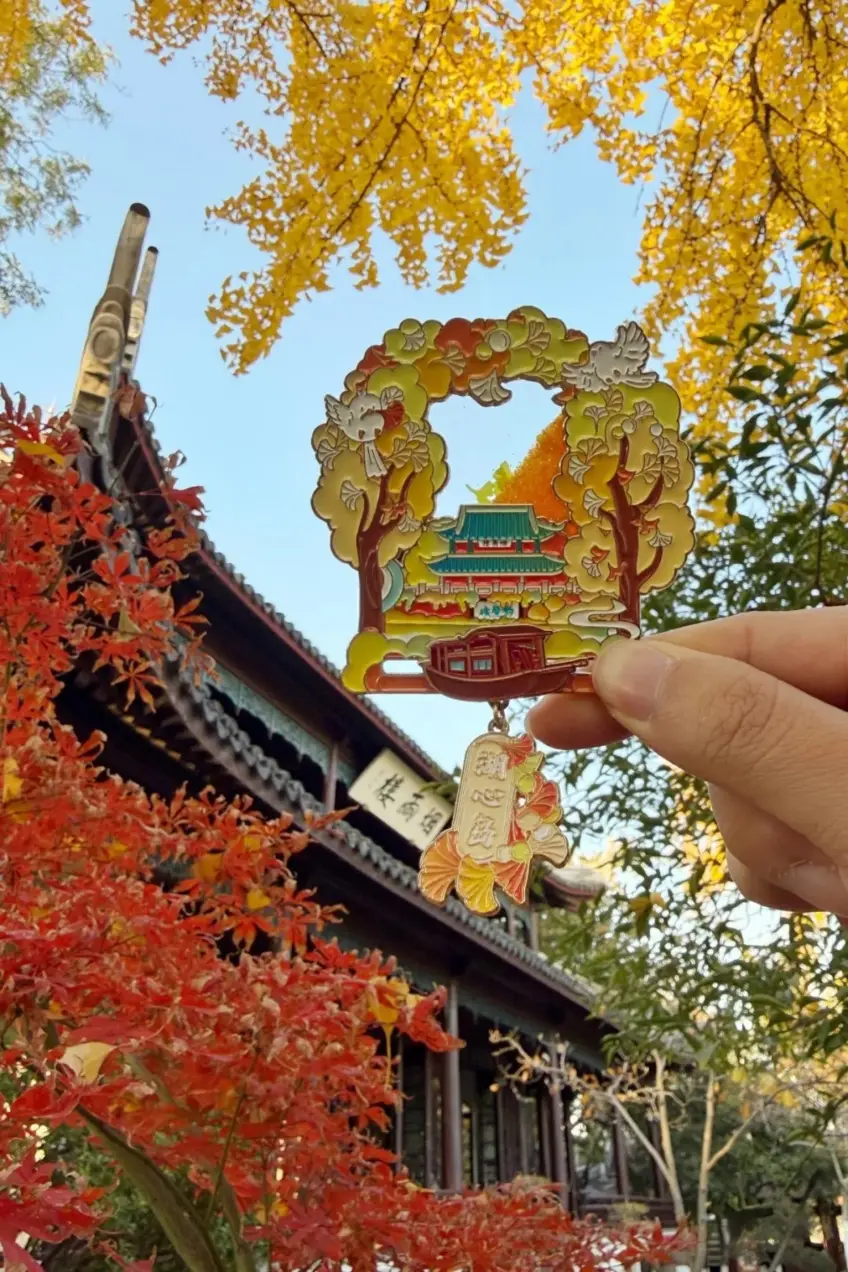 手持湖心岛建筑红船银杏图案冰箱贴，背景亭廊秋色