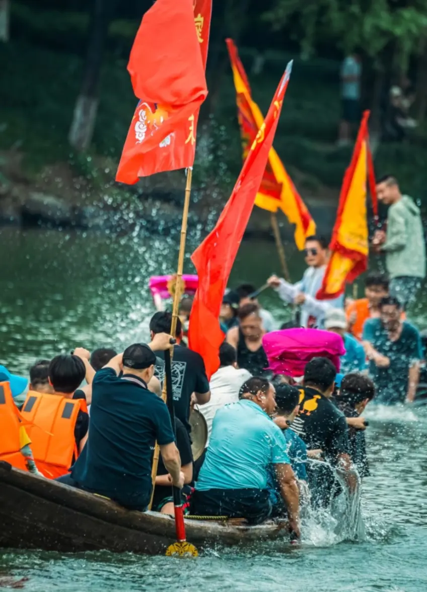 龙舟上红黄彩旗与桨手浪花