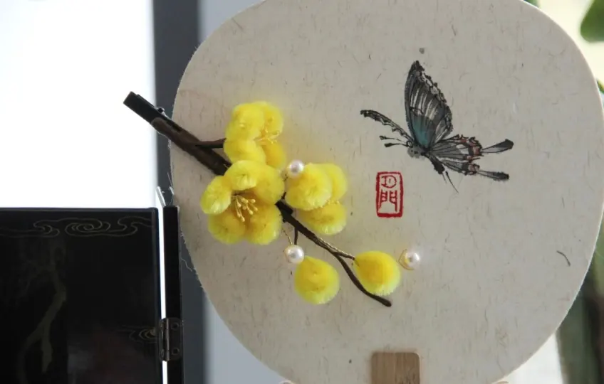 团扇上贴黄绒花枝与蝶绘朱印