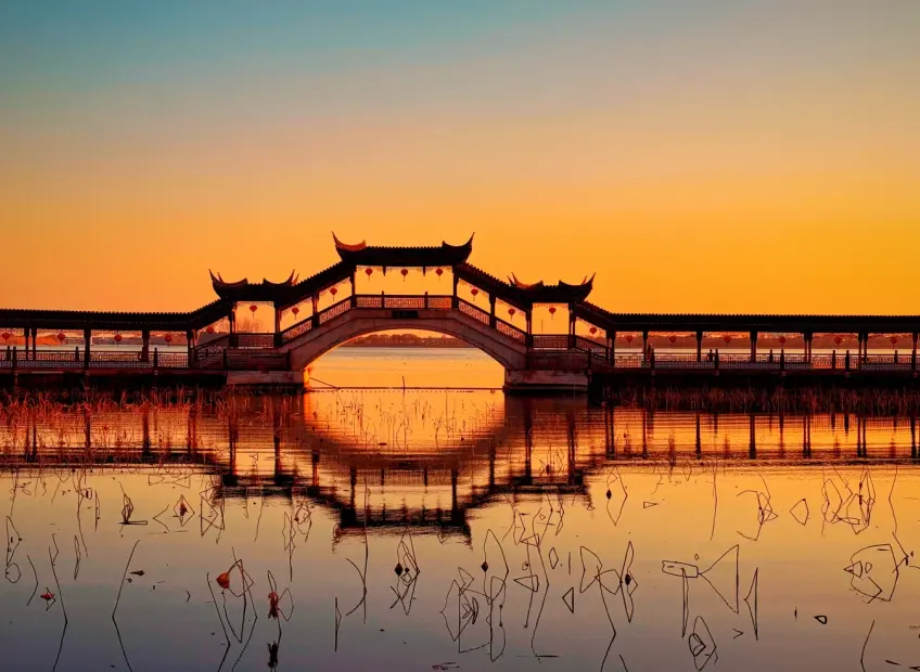 夕照廊桥倒影与枯荷水面
