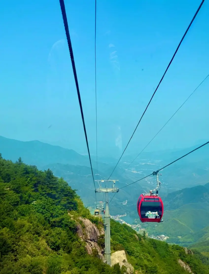 索道轿厢内俯瞰红色车厢与山谷湖