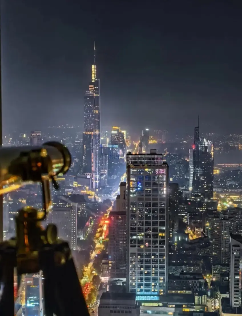 酒店窗邊望遠鏡俯瞰紫峰大廈夜景豎向示意