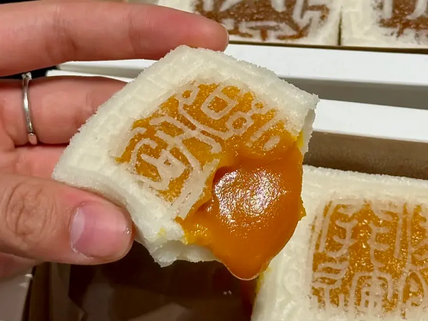 手持咬开橙馅的方形糕团特写