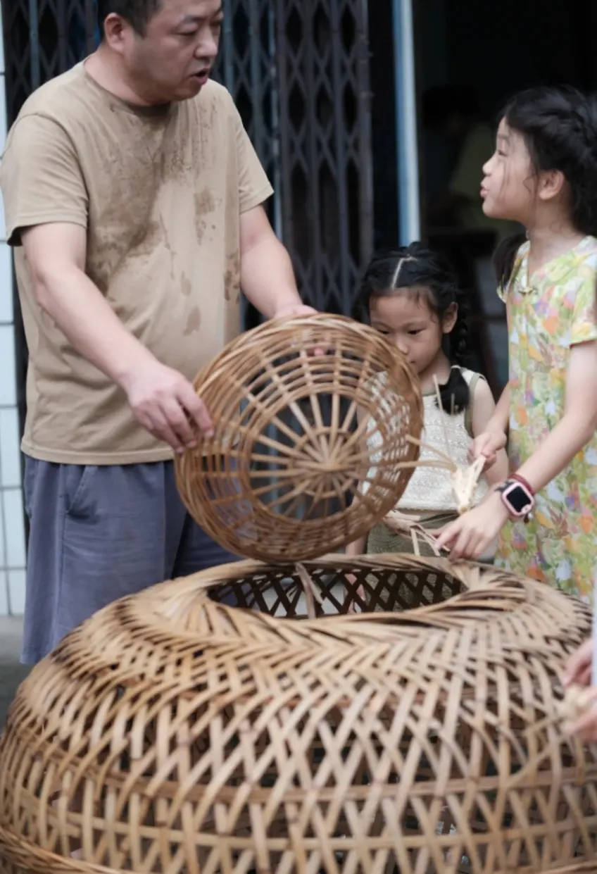 老师傅教孩子编织竹编圆盖手艺