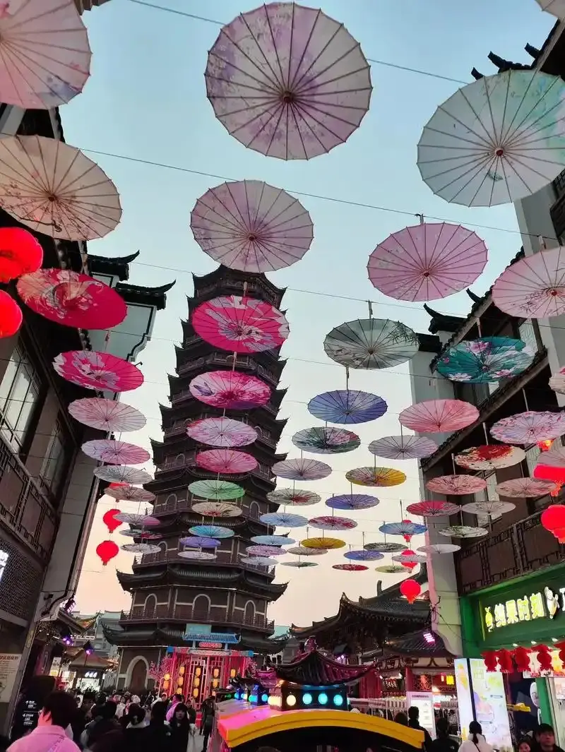 彩色油纸伞下古街夜市与远处塔影