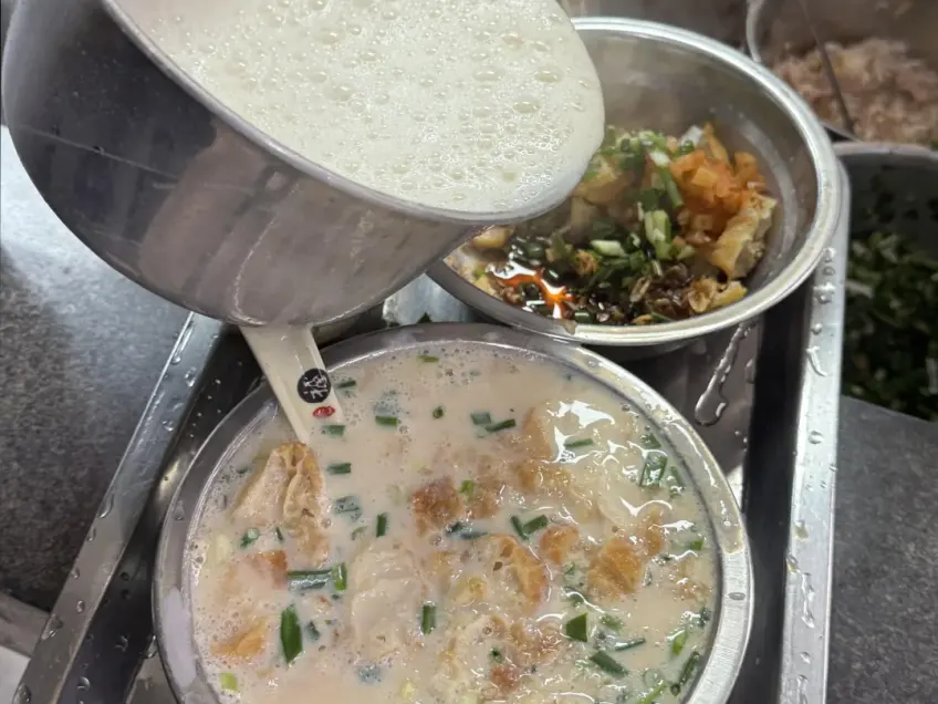 早餐摊金属碗里现冲咸豆浆与油条葱花