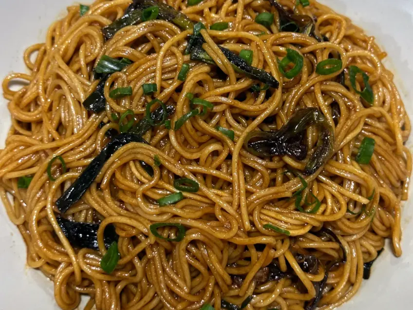 白瓷盘里葱油拌面与焦葱段装盘