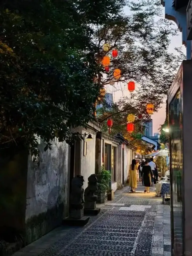 黄昏灯笼下石板小巷行人悠闲走过
