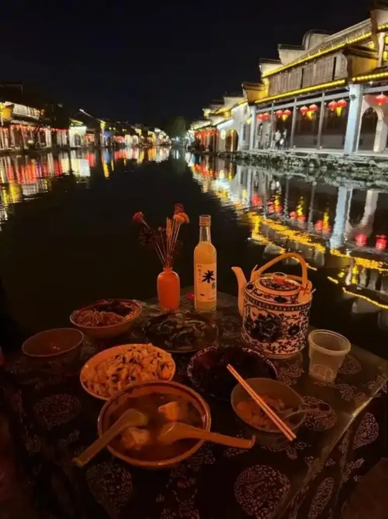 古镇河边夜宴餐桌与对岸红灯笼倒影