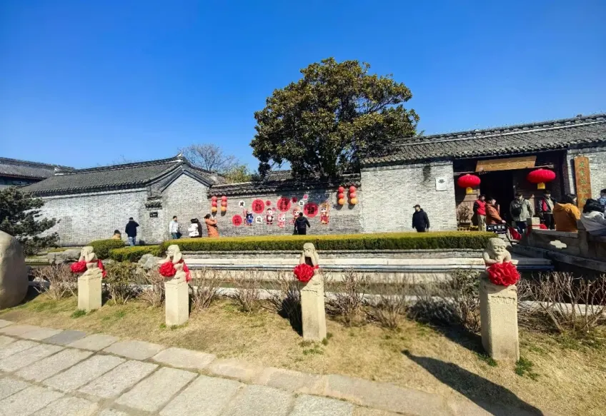 故居外墙石兽红绸树影与红灯笼门