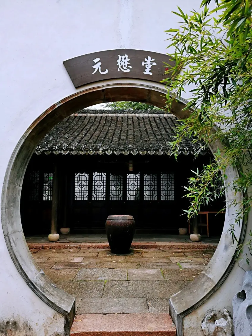白墙月洞门内扇形匾额与石院陶缸