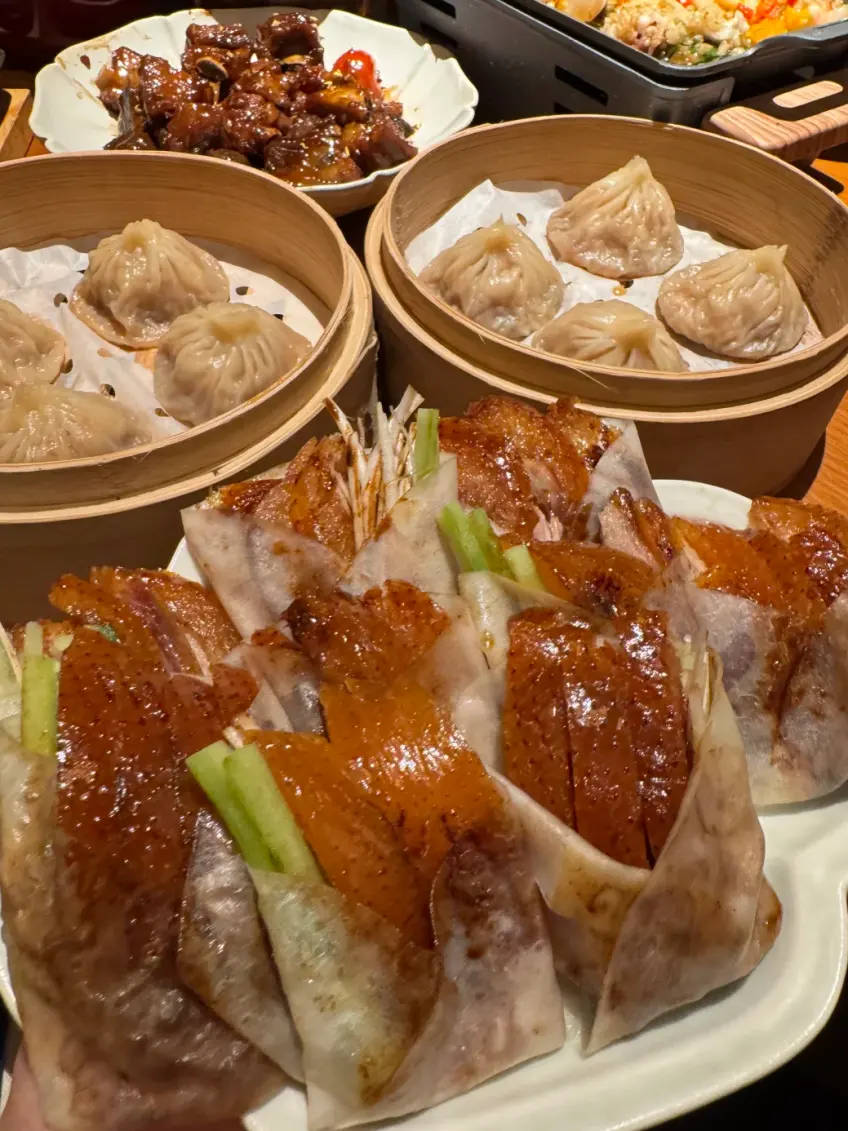 桌上烤鴨捲餅竹籠湯包與配菜拼盤