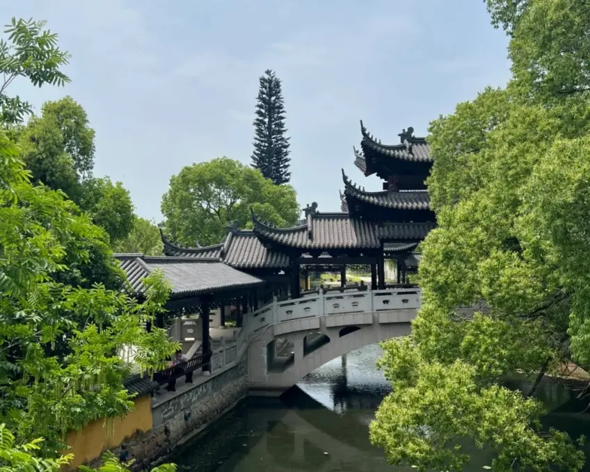 多层廊桥飞檐跨窄河与绿树