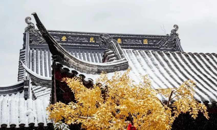 雞鳴寺黃牆銀杏葉與雪覆灰瓦屋頂