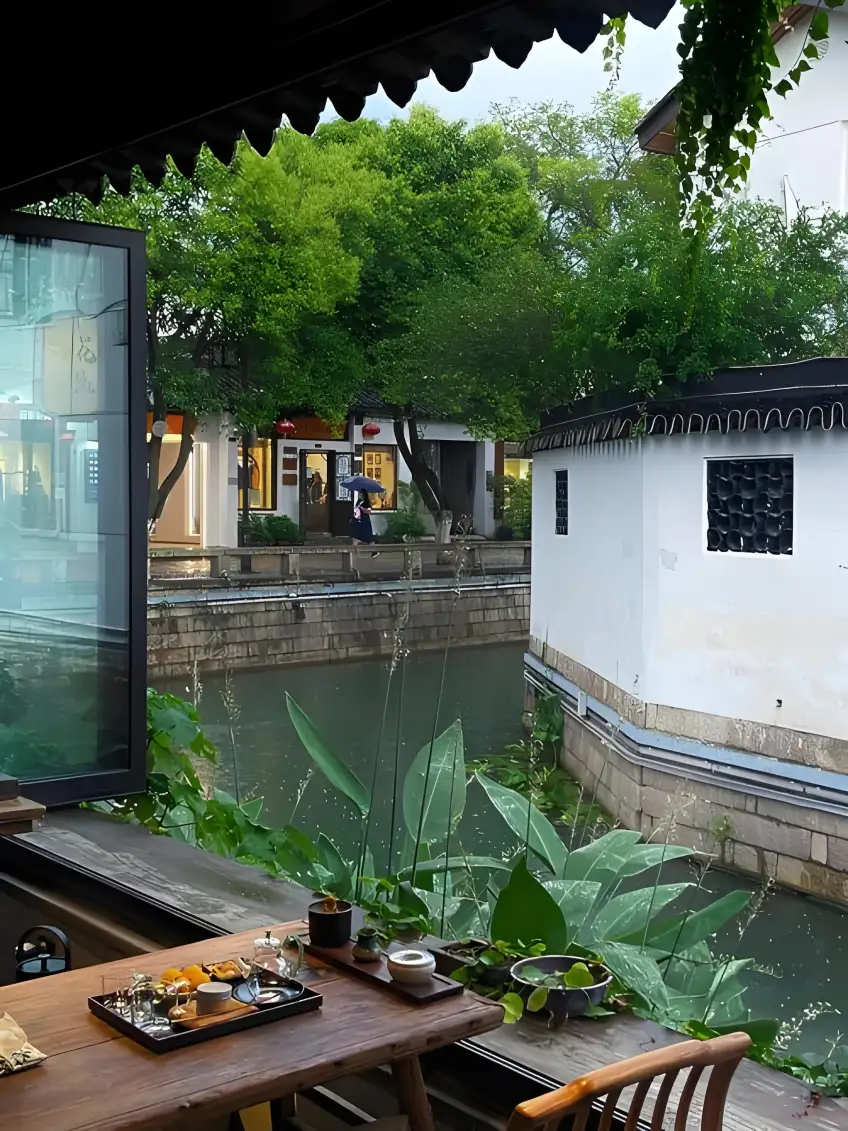古鎮茶座靠窗俯瞰窄河道白牆雨傘