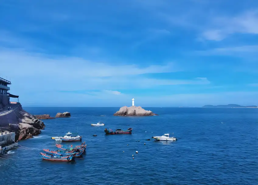 舟山海島白色燈塔與藍海漁船遠景