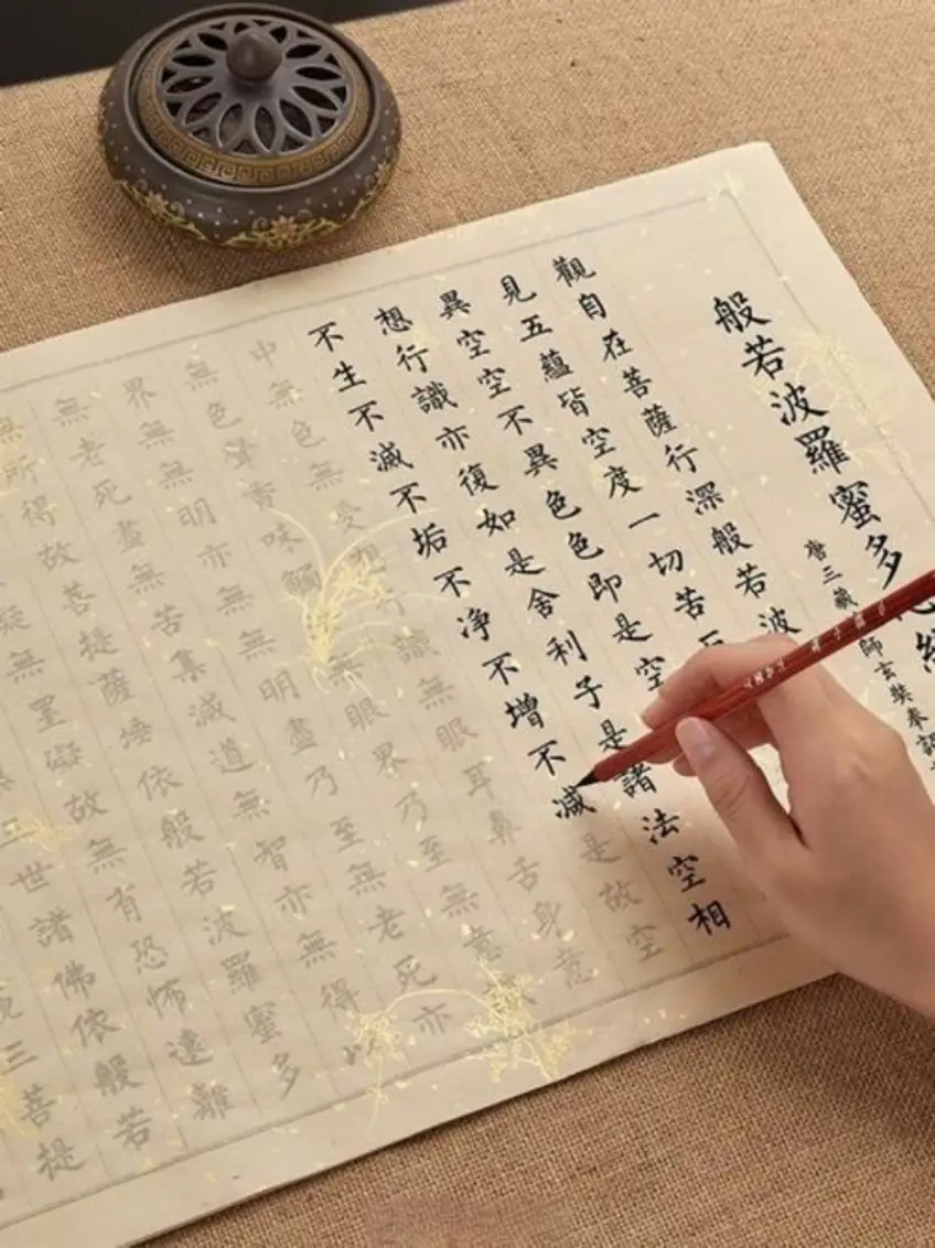 手持毛筆在抄經格紙書寫心經