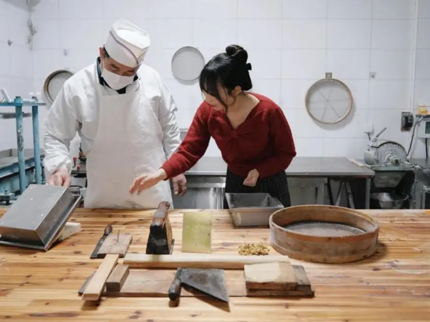 作坊師傅戴帽與遊客案臺製作糕點