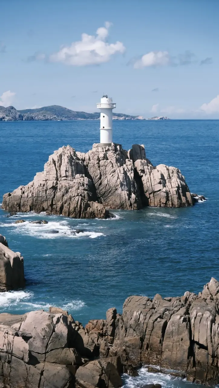 海邊礁石上白色燈塔立於碧海