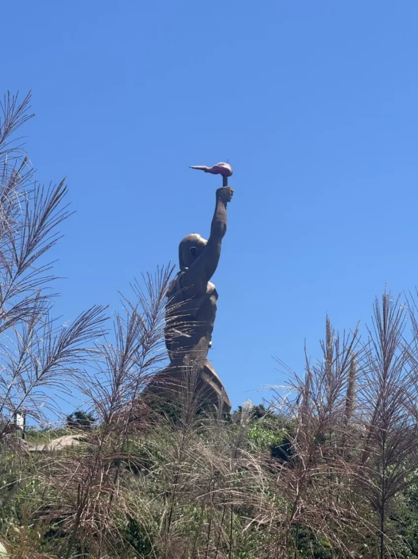 蘆葦前景下高舉火把的財伯公雕像